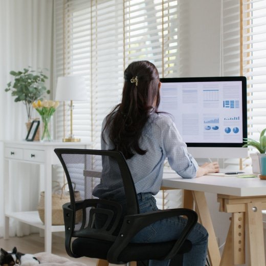 A woman sitting at a desk looking at a computer screen.