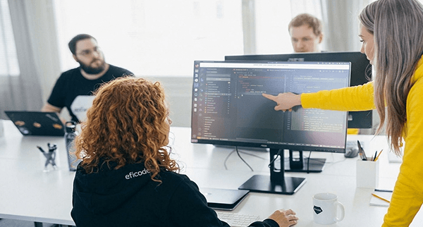 Two developers looking at big screens with lines of code.