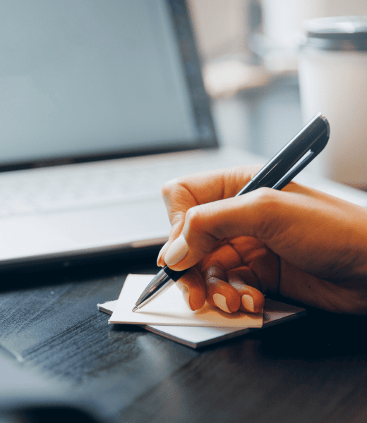 A hand holding a pen to write something down.