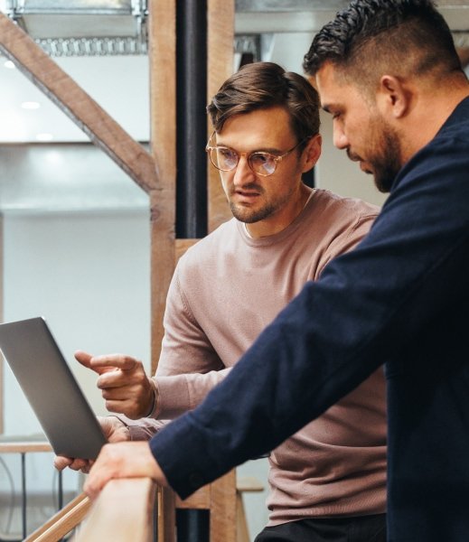 Two men looking at a tablet screen and discussing.