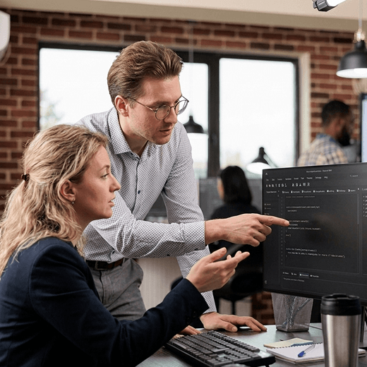 Two people looking at data at a computer screen.