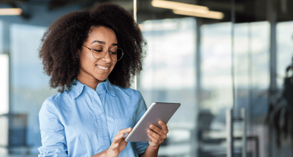 A woman looking at a tablet. She is smiling.